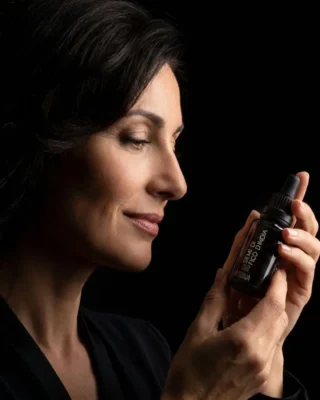 Come leggere l'INCI nella cosmesi naturale. L'immagine cattura il momento della scelta consapevole: una donna sofisticata verifica la purezza dell'Olio di Fico d'India spagirico, simbolo del lusso etico e della trasparenza totale di Primaessenza.